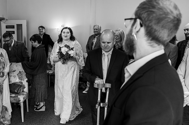 Bride walking down aisle with bouquet and guests