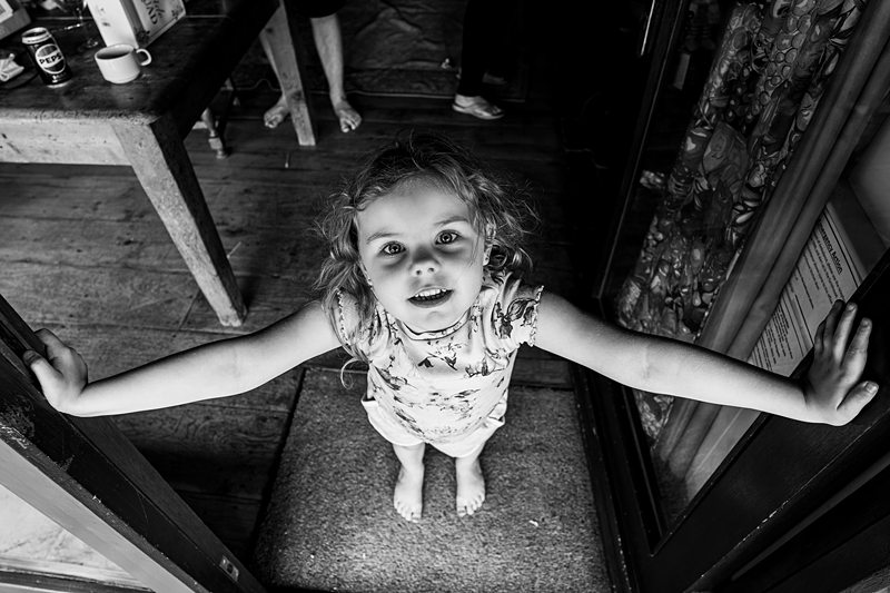 Child smiling with arms outstretched in doorway.