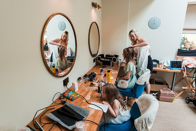 Hairdresser styling hair for young girls in salon.