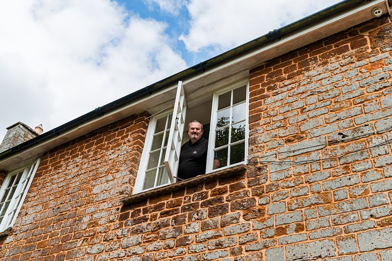Man leaning out of brick building window.
