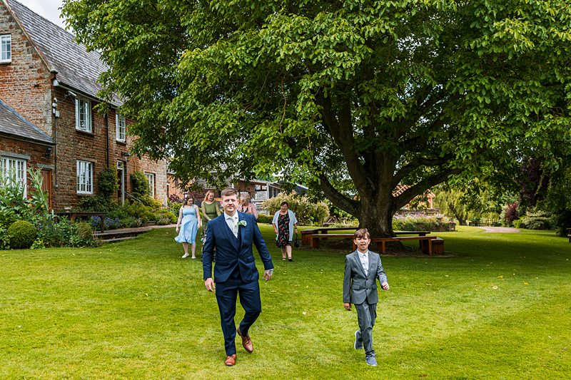 Wedding guests walking on green lawn.