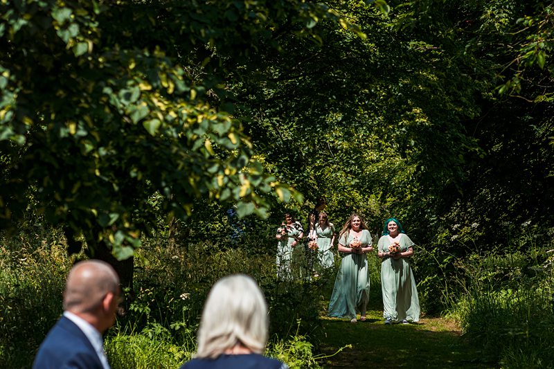 Bridesmaids walking down a forest path.