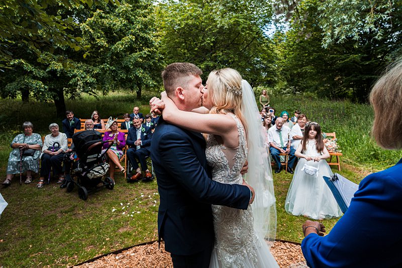 Newlyweds kiss at outdoor wedding ceremony