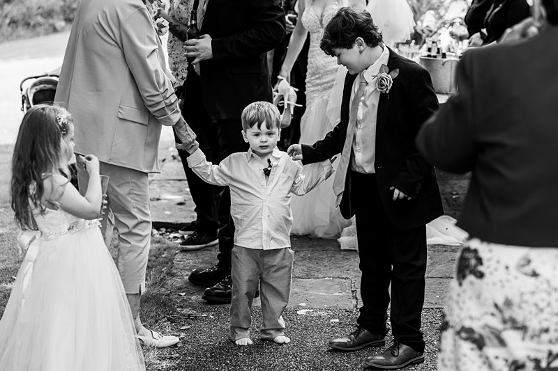 Children at wedding ceremony outdoors, holding hands.
