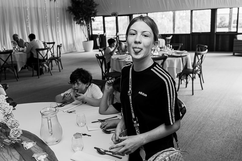 Young girl playfully sticking out tongue at restaurant.