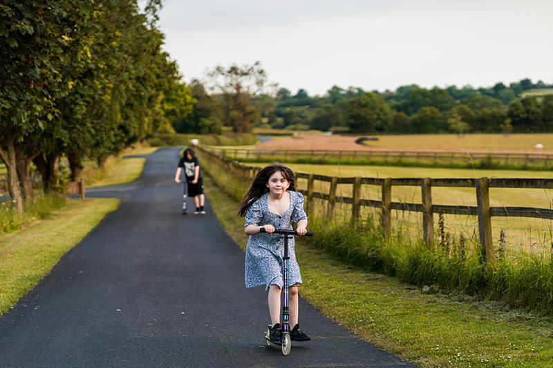 Children riding scooters on rural path