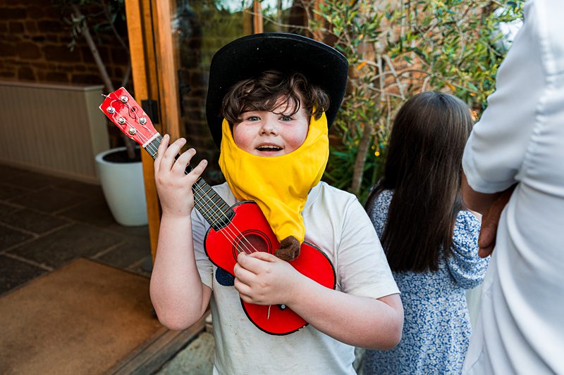 Child dressed as cowboy with red guitar