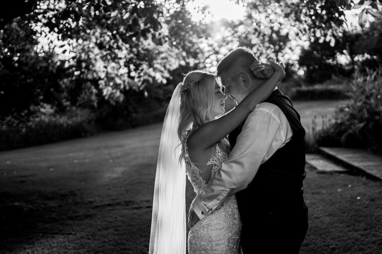 Bride and groom embracing in garden