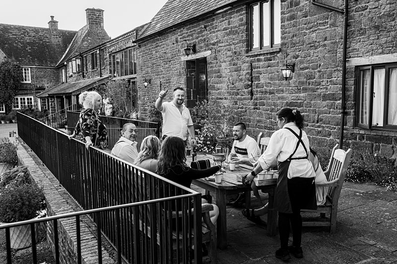 People dining outdoors at countryside stone house.