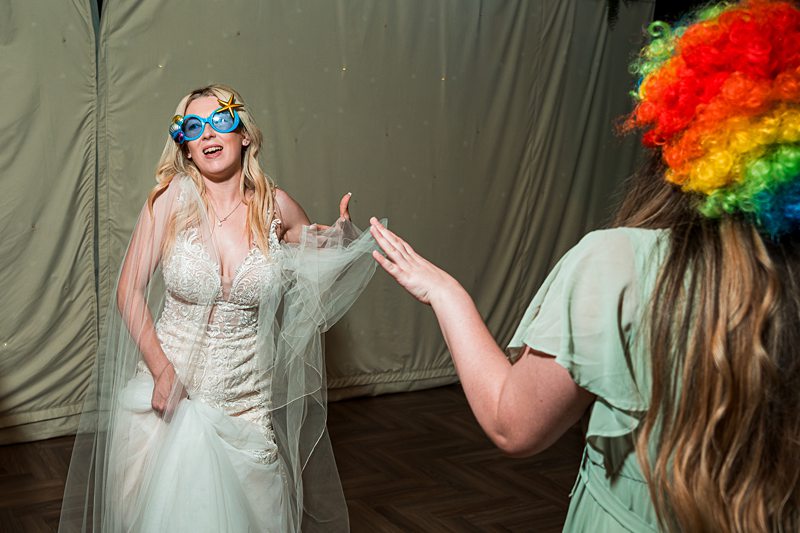 Bride with funny glasses and woman in rainbow wig.