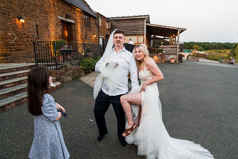 Bride and groom posing outside rustic wedding venue.