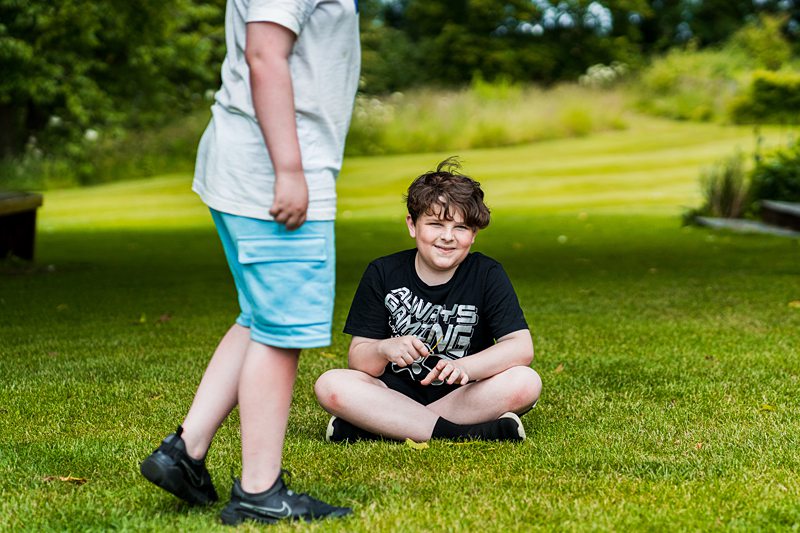 Boys sitting and standing on green grass