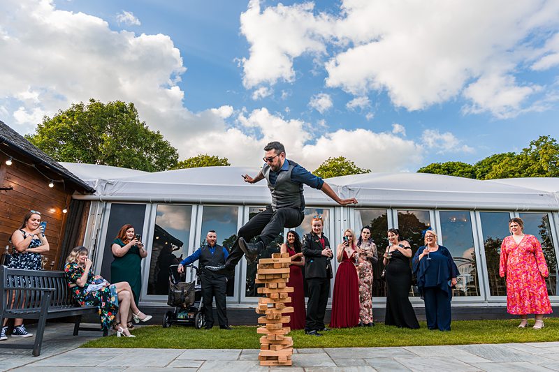 Man jumping on giant Jenga blocks at party.