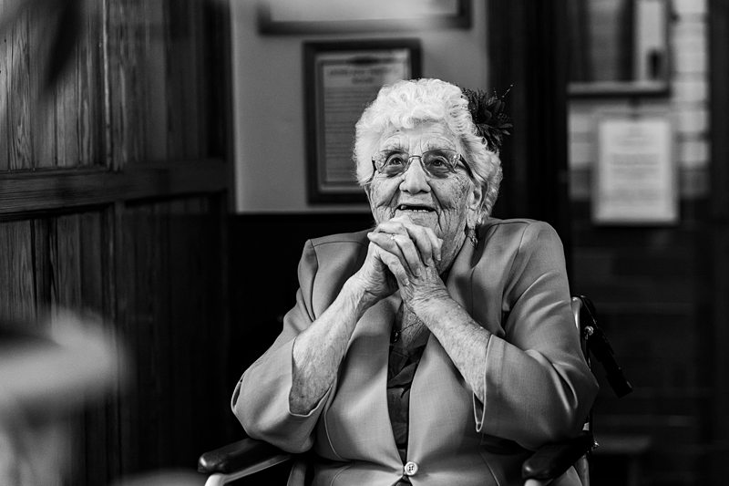 Elderly woman smiling in black and white portrait.