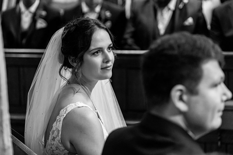 Bride in veil during wedding ceremony, black and white