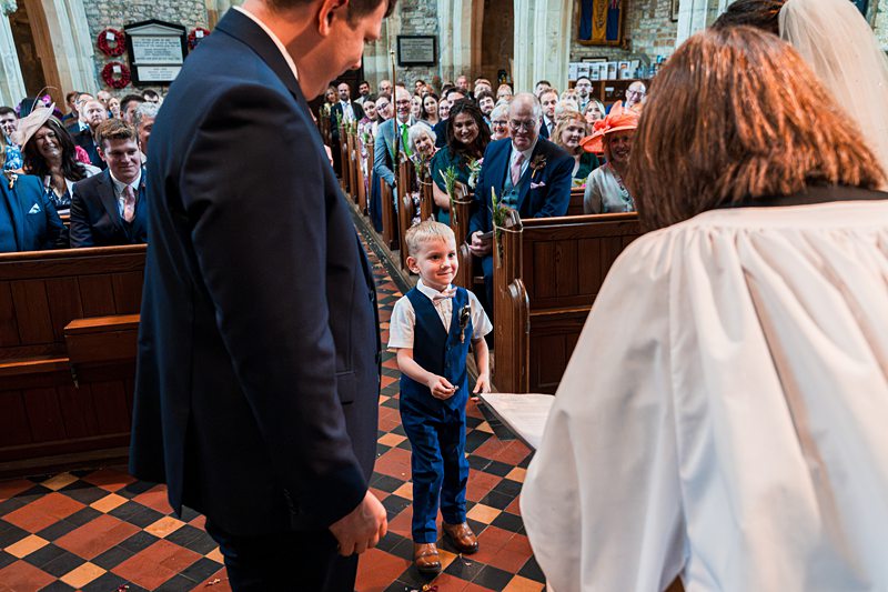 Young boy smiling at wedding ceremony in church.