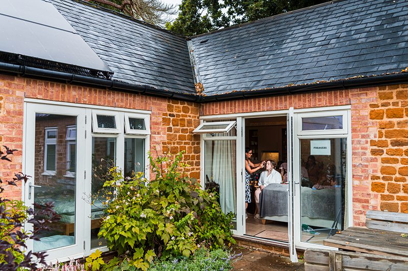 Hairdresser styling client through open patio doors.