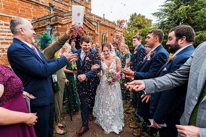 Confetti thrown at newlyweds exiting church ceremony.