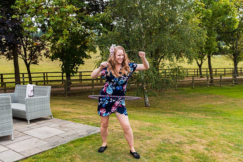 Woman hula hooping in garden, smiling.