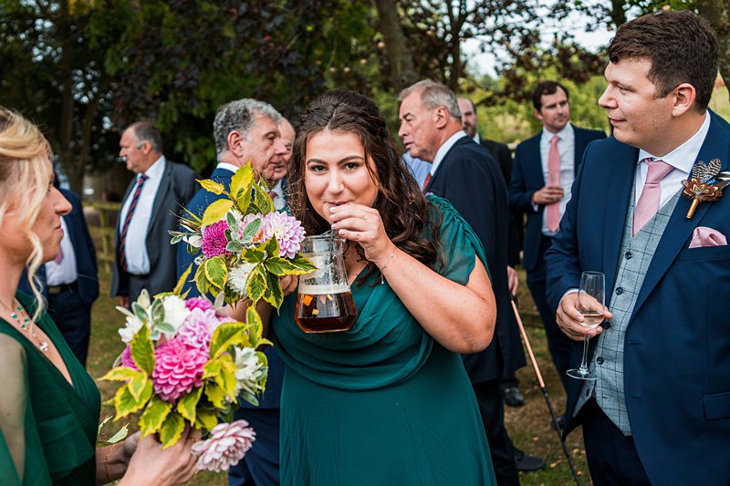 Wedding guests enjoy drinks and flowers outdoors.
