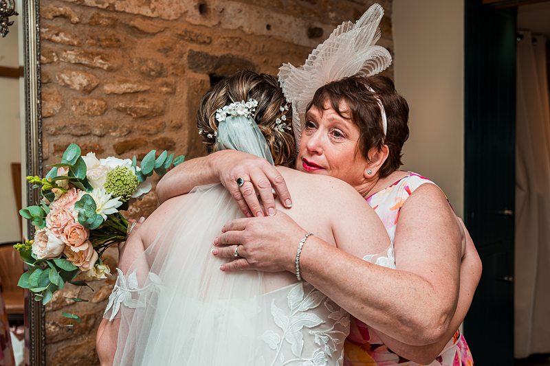 Bride hugging woman, holding bouquet, joyful expression