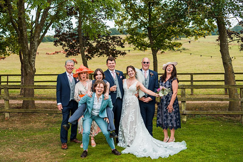 Wedding guests pose joyfully in outdoor setting.