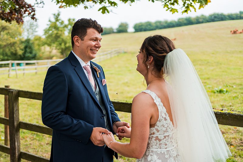 Bride and groom smiling outdoors on wedding day.