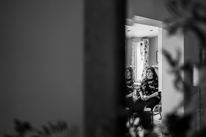 Woman reflected in a mirror, sitting indoors.