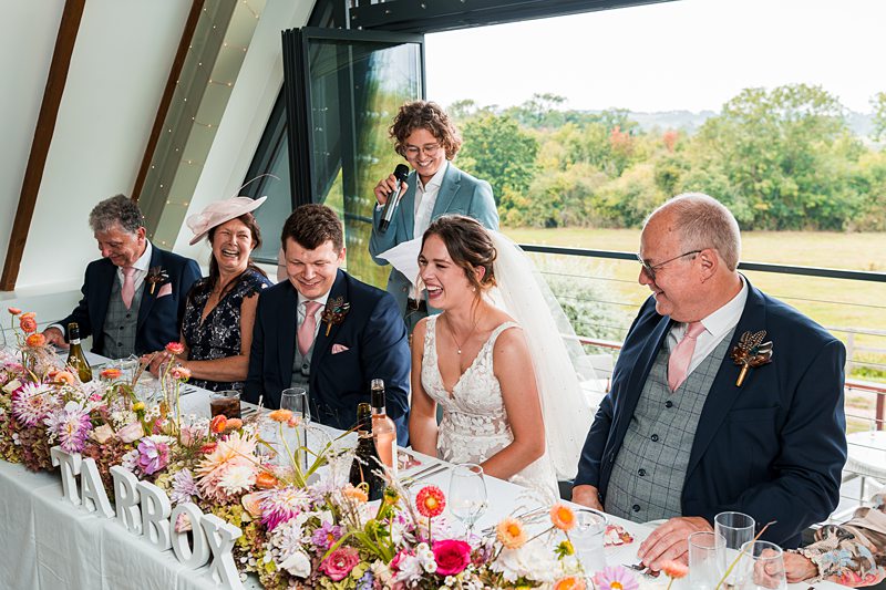 Wedding couple laughing at reception speech.