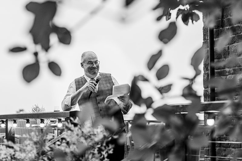 Man giving speech outdoors, holding notes.