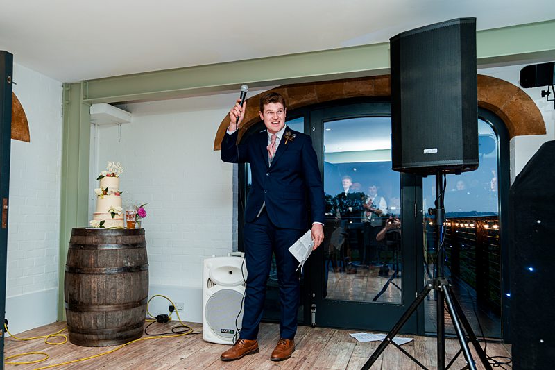 Man giving a speech at wedding reception.