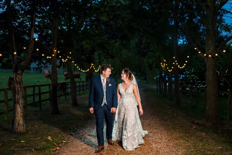 Bride and groom walking under fairy lights.