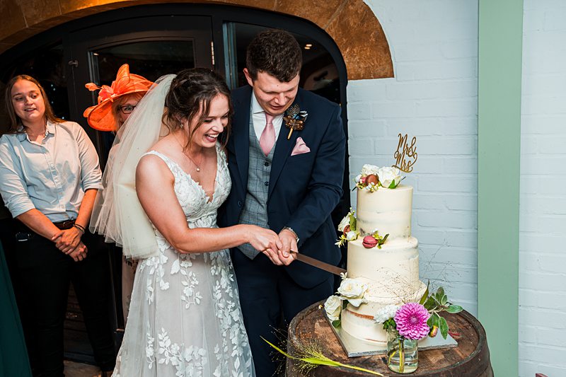 Bride and groom cutting wedding cake.