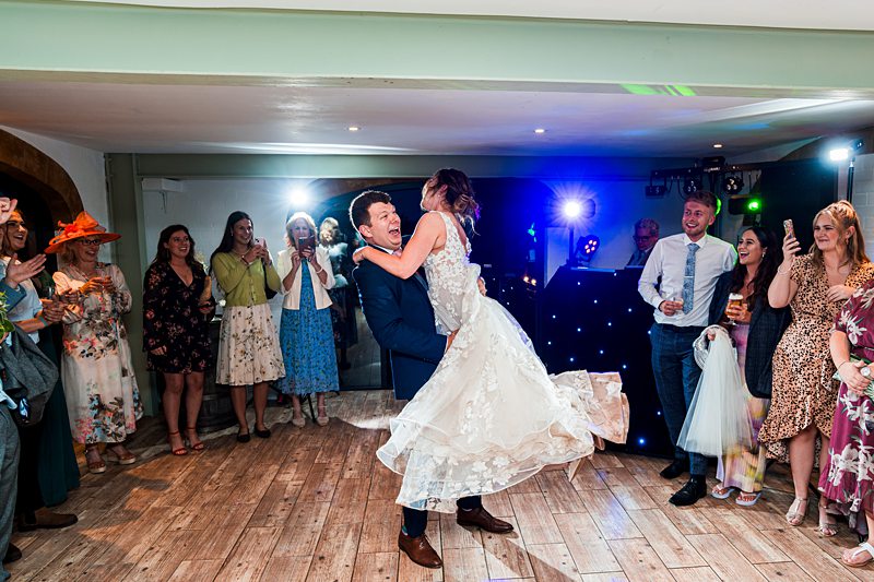 Bride and groom dancing at lively wedding reception.
