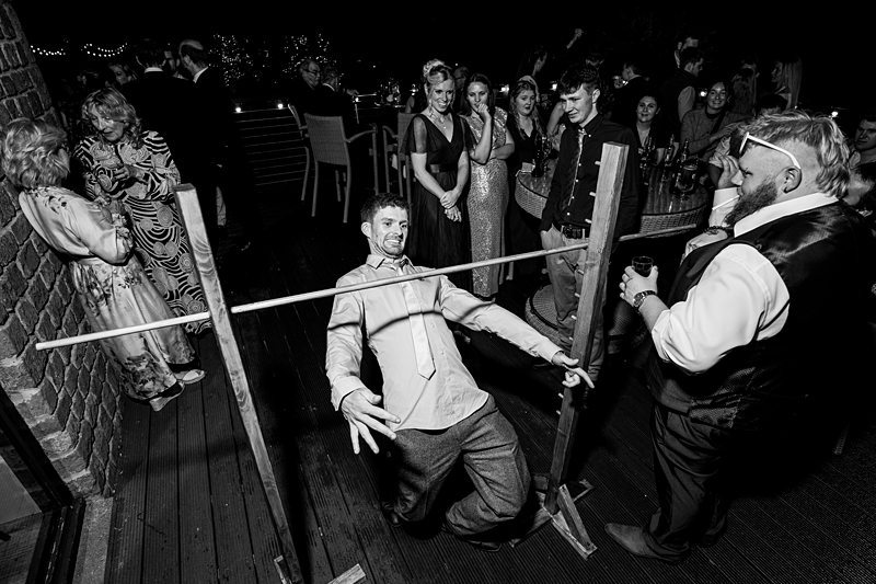 Wedding guests playing limbo game at party.