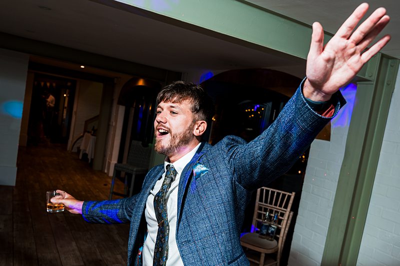 Man in suit celebrating with a drink.