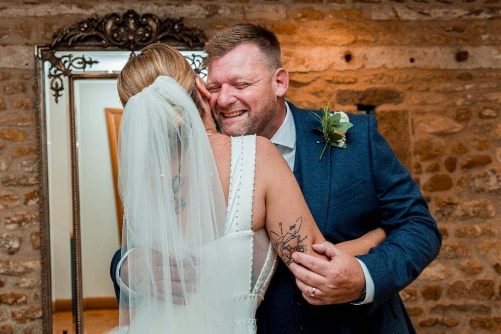 Bride and groom hugging, smiling joyfully.