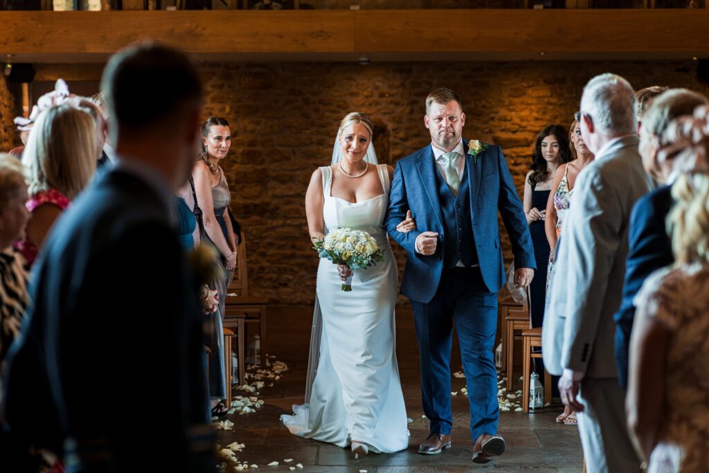 Bride walking down aisle with father at wedding