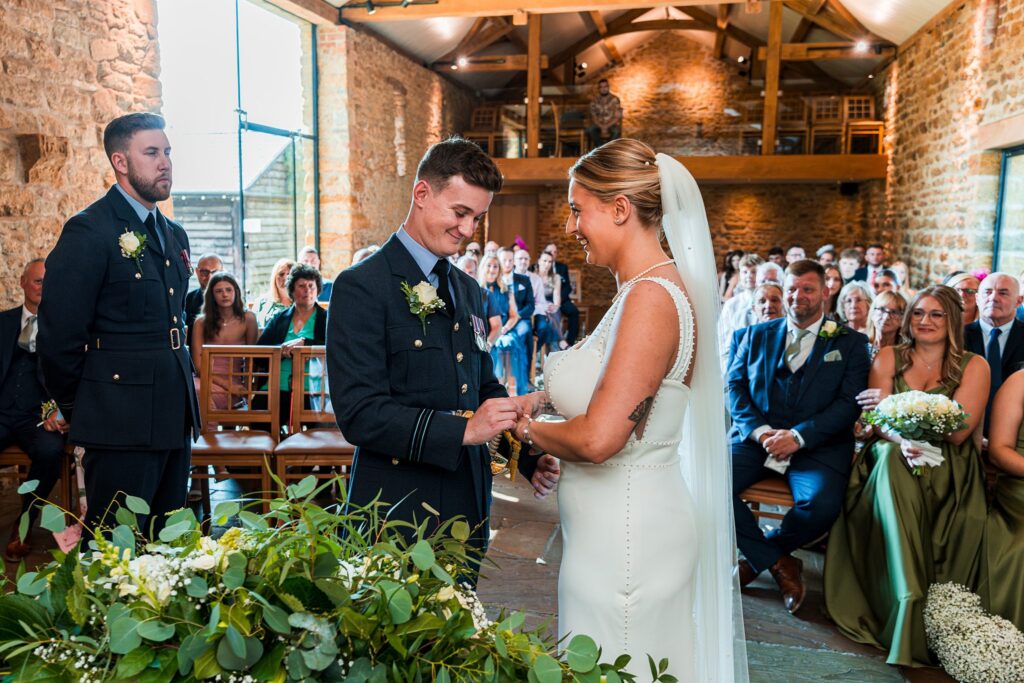 Bride and groom exchanging rings in rustic venue.