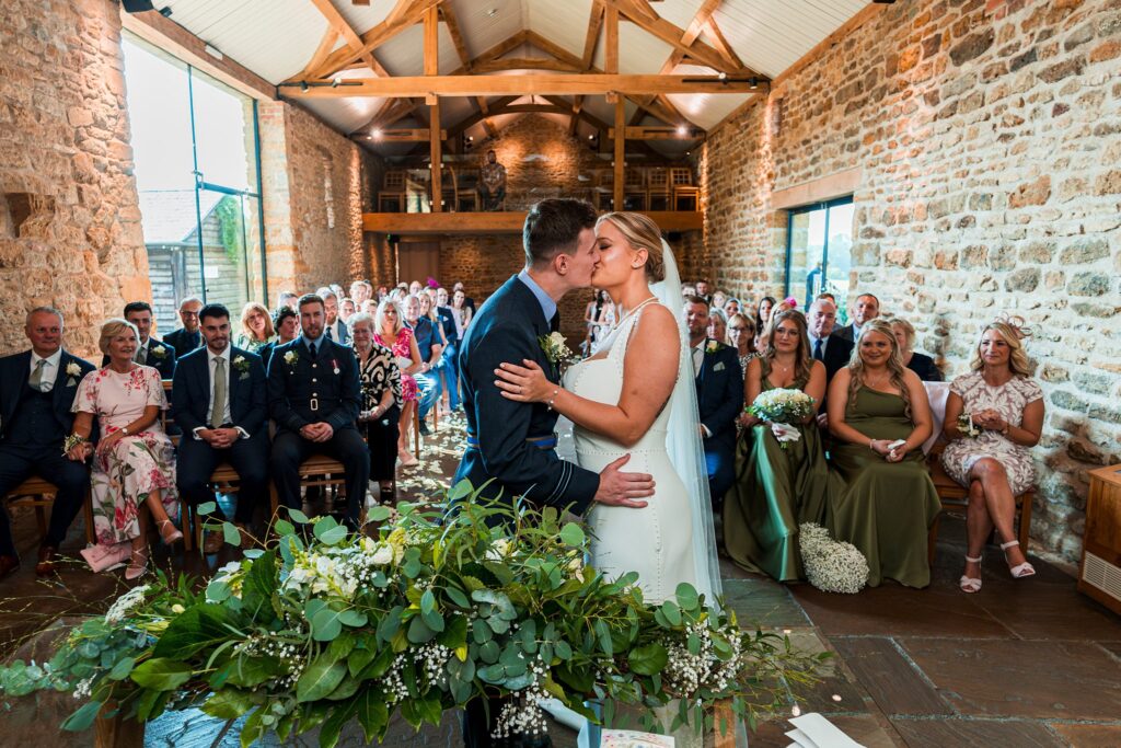 Couple kissing at rustic wedding ceremony.