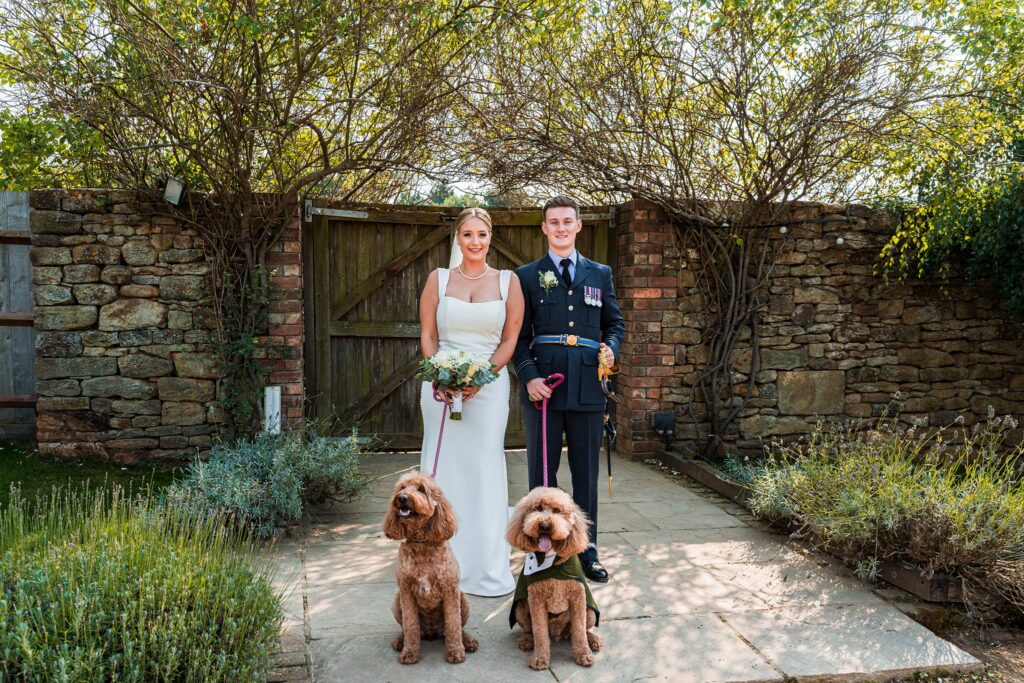 Bride, groom, two dogs, outdoor wedding photo.