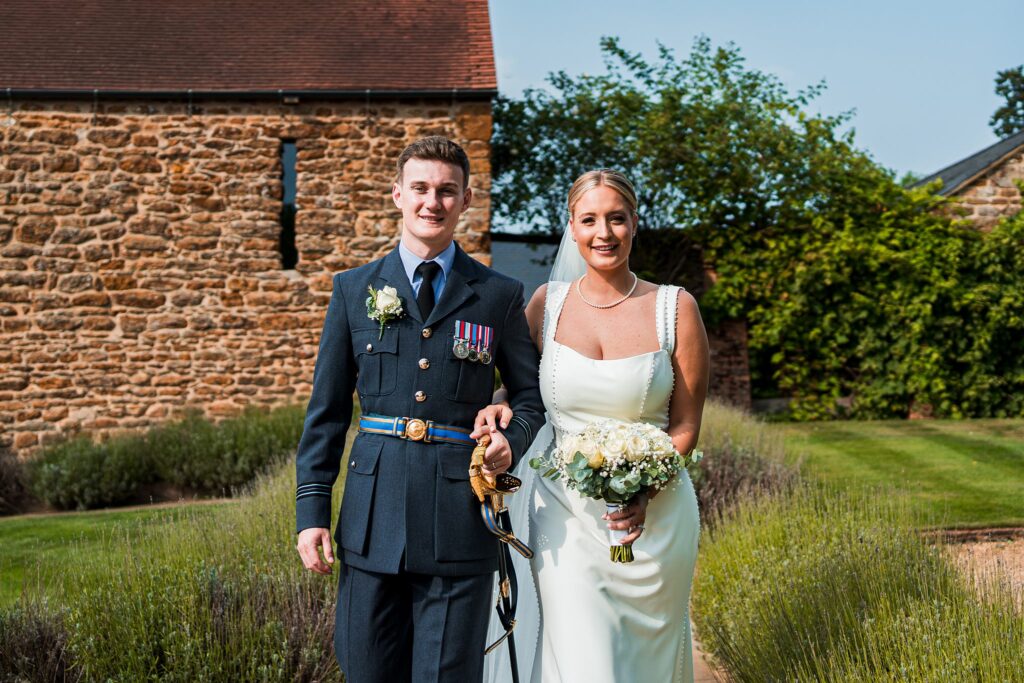 Bride and groom smiling outside rustic barn.
