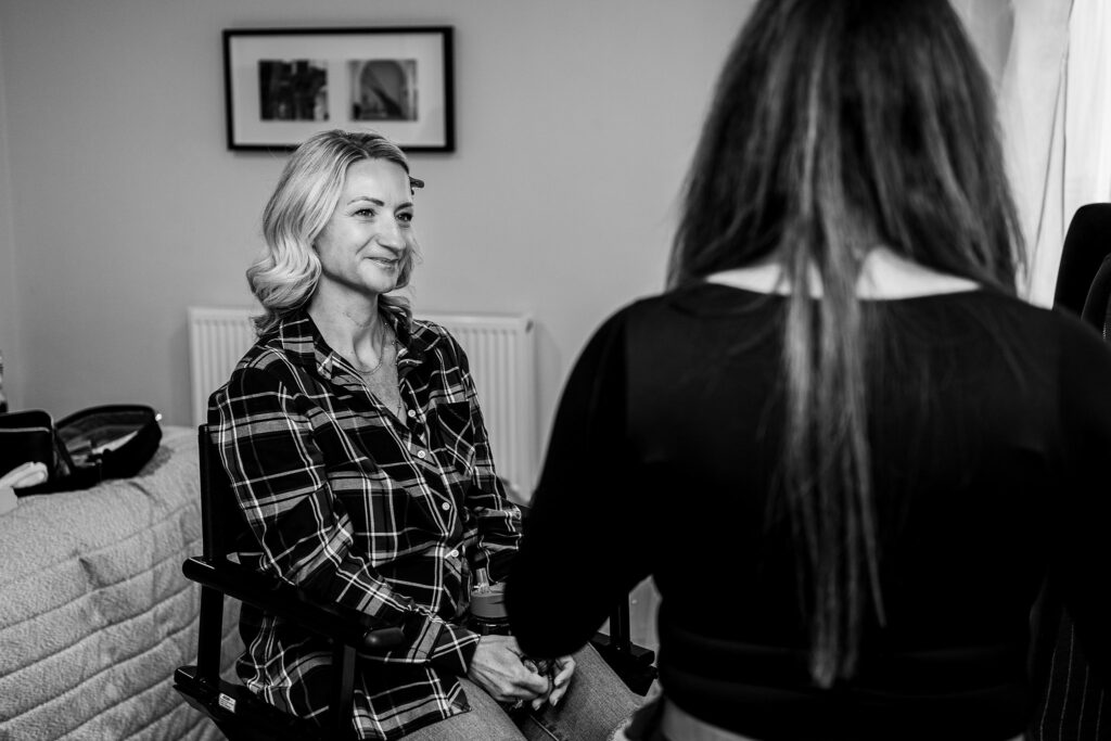 Woman getting makeup done, smiling in chair.