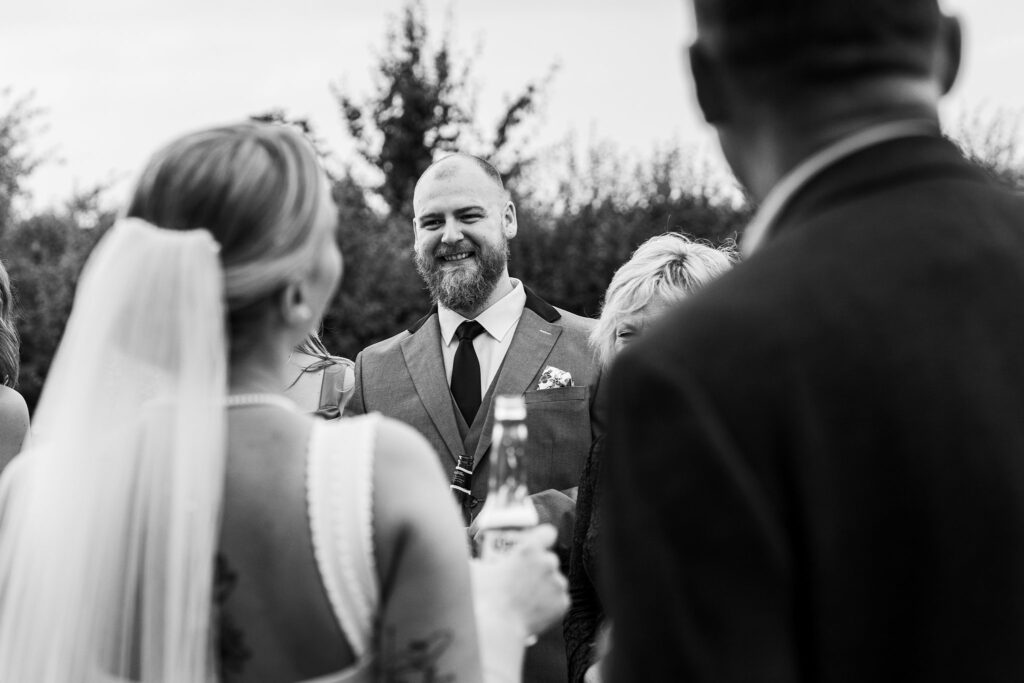 Wedding guests smiling and talking together outdoors.