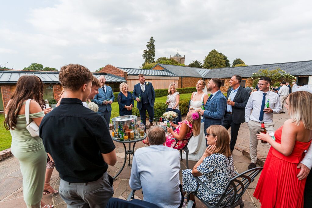 Wedding guests socialising outdoors, drinks in hand.