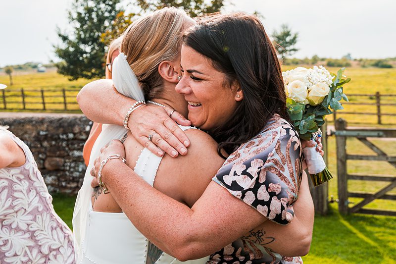 Women hugging at outdoor wedding ceremony