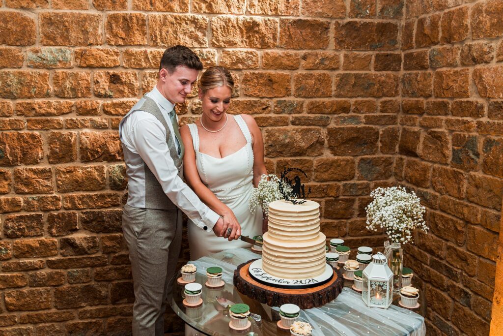 Bride and groom cutting wedding cake together.