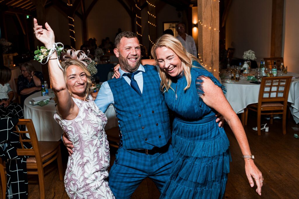 Three people dancing joyfully at a festive event.