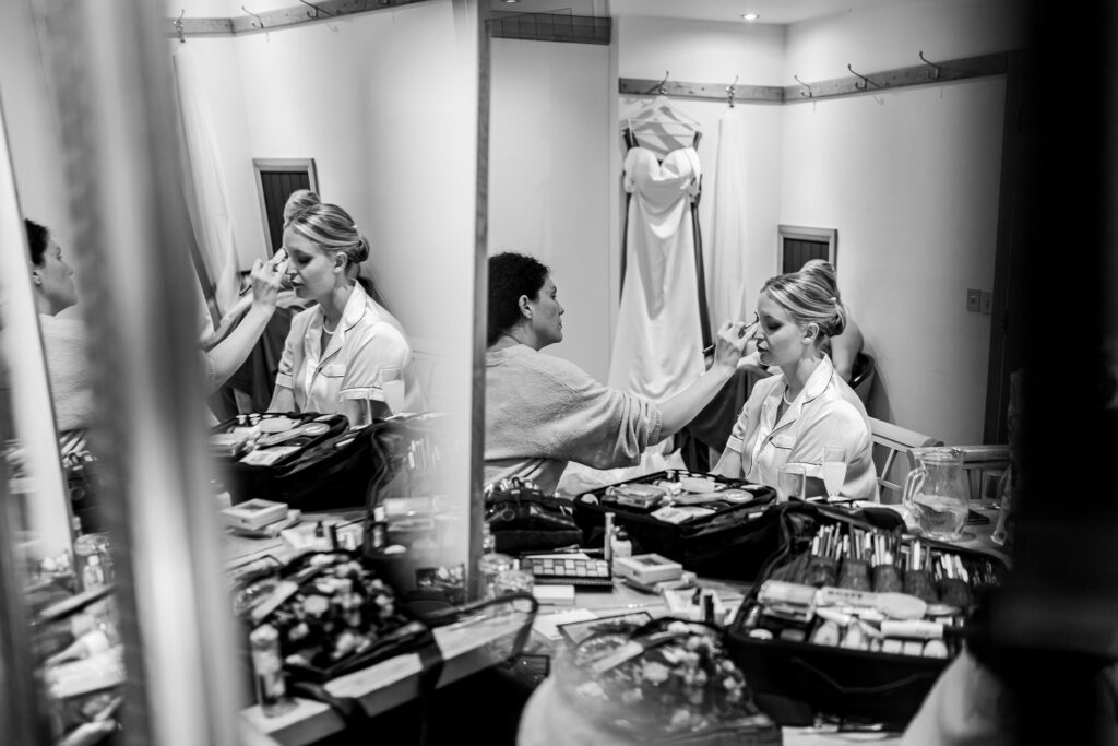 Bride getting makeup in dressing room.