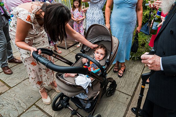 Woman tends to baby in pram at gathering.